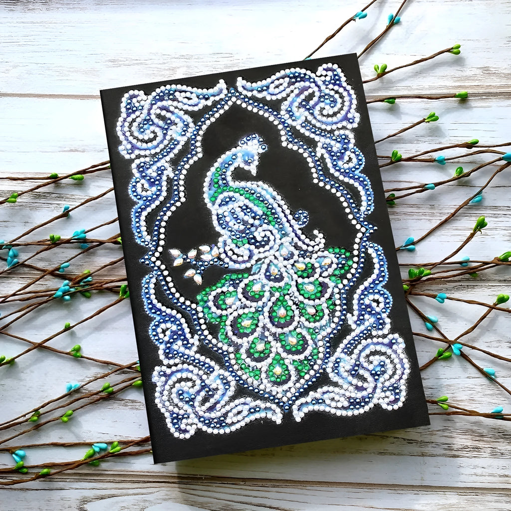 Peacock design diamond painting kit on a black A5 hardback notebook with drills and tools