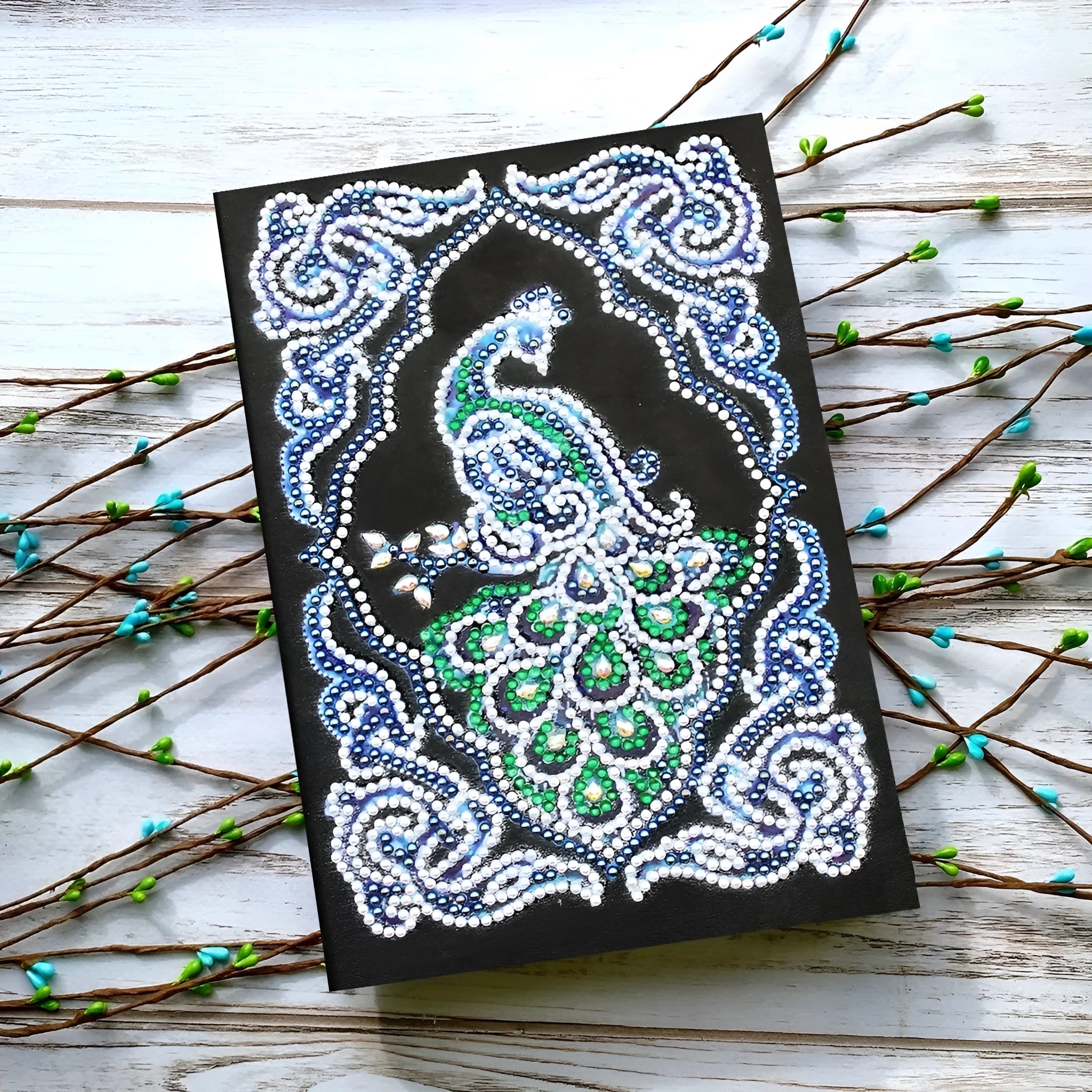 Peacock design diamond painting kit on a black A5 hardback notebook with drills and tools