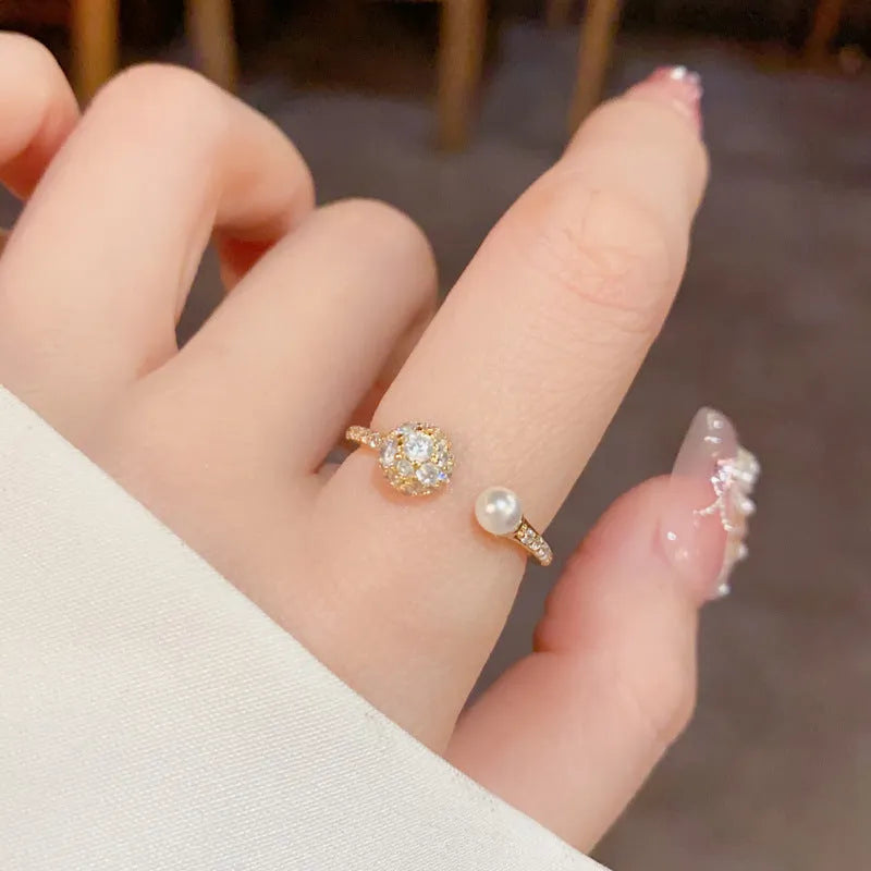 Gold or silver coloured open-end ring with a round zircon pearl on a geometric band.