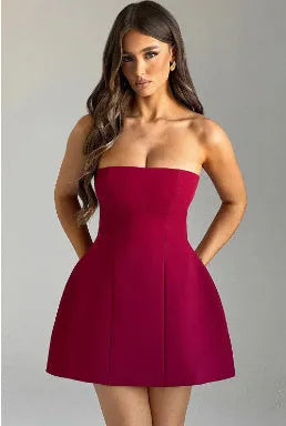 A backless solid colour tube dress on a model, showing its high waist and short A-line skirt.