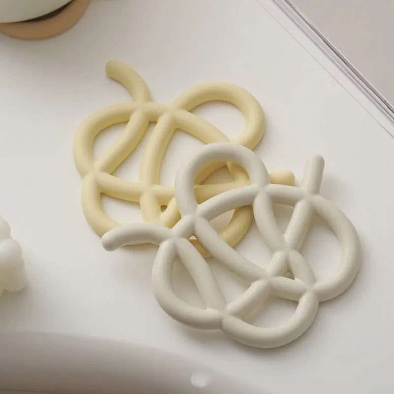 Irregular-shaped ceramic heat proof mat with hook and loop backing on a wooden table.