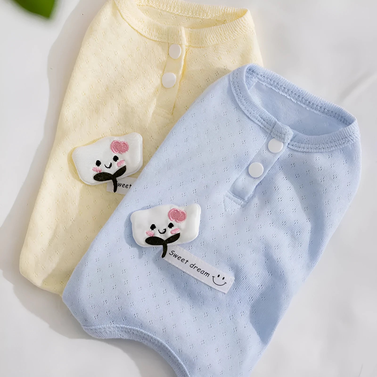 Soft yellow mesh pet shirt with cartoon cat patch and button closure on a small dog or cat