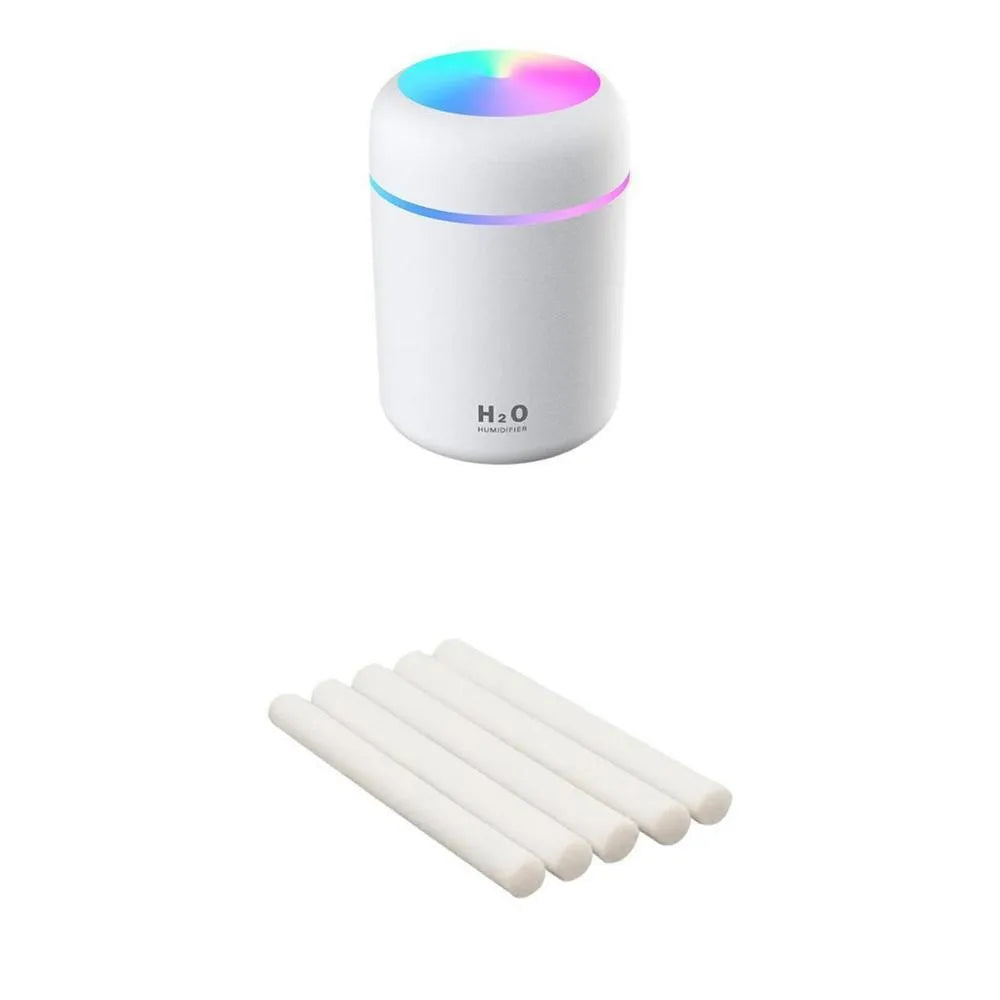 Pink USB mini humidifier with LED lights on wooden desk beside laptop