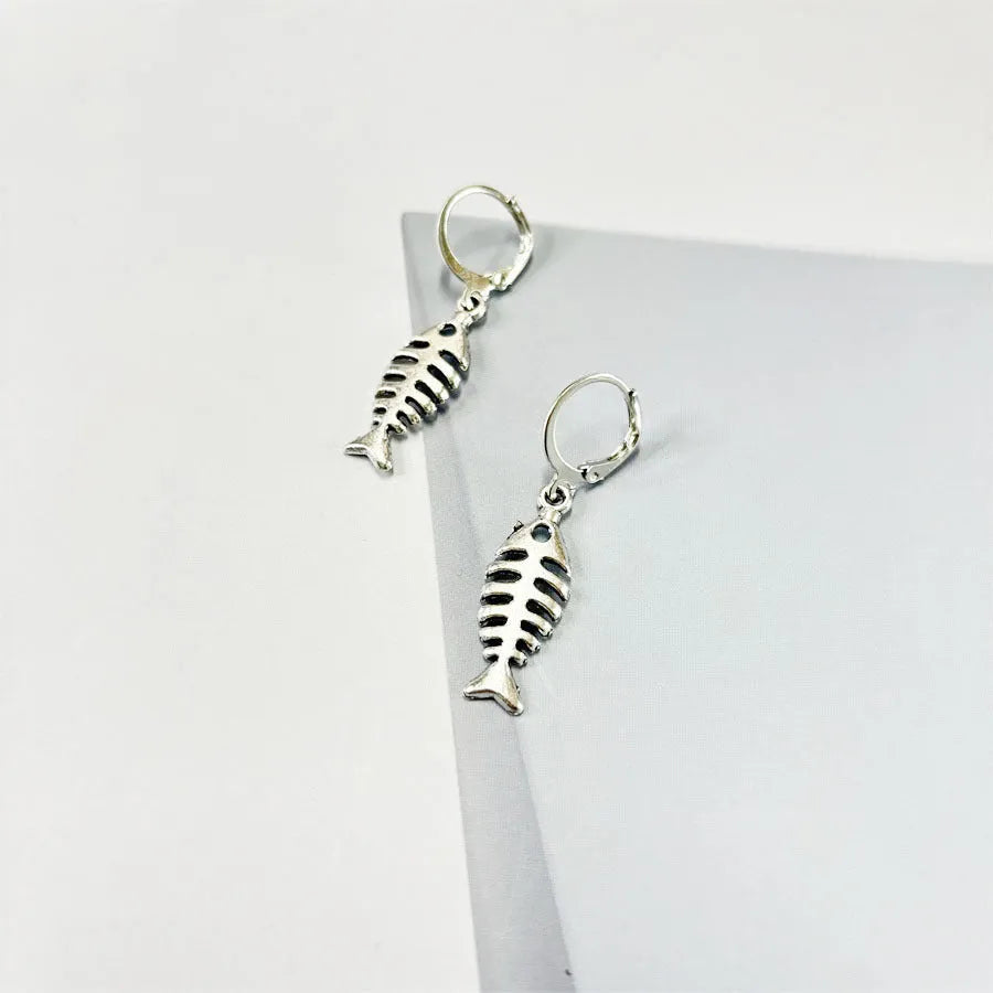 Close-up of retro-style fishbone pendant earrings on an adjustable O-chain.