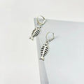 Close-up of retro-style fishbone pendant earrings on an adjustable O-chain.