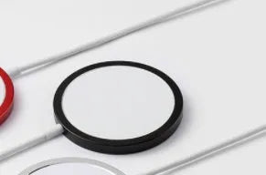 Silver metallic MagSafe-compatible magnetic wireless charger for iPhone on a wooden desk.