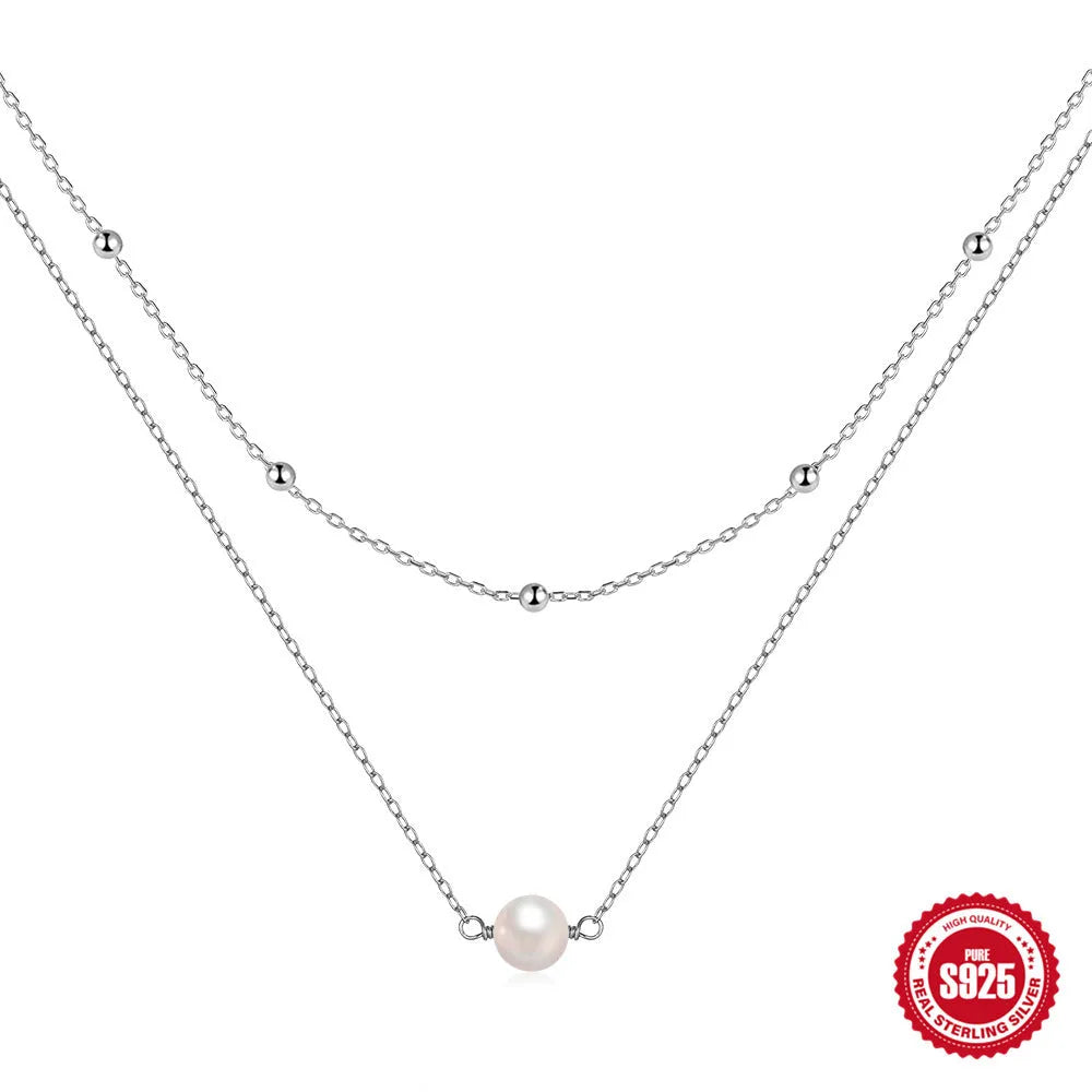 Women's double layer sterling silver necklace with geometric pendant and twin pearls, shown in gold and white gold plating.