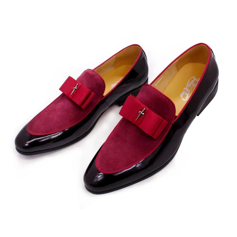 Men's black tassel loafers with matte and glossy patent leather uppers and a rubber sole, shown on a wooden surface.