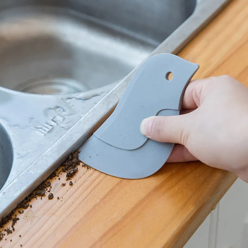 Penguin-shaped soft blade kitchen scraper tool for cleaning plates and pans in green, grey, or pink colours