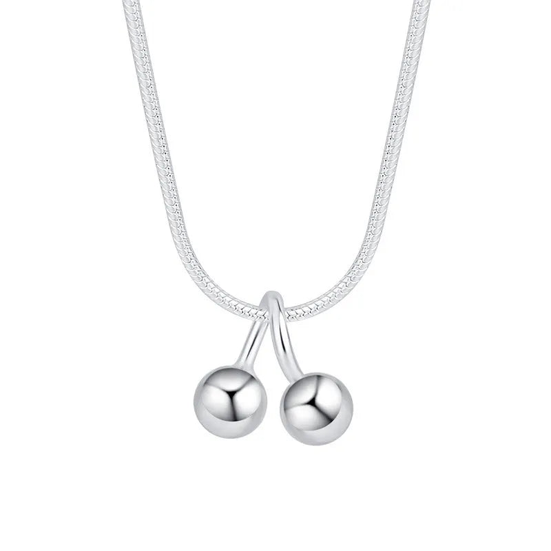 Close-up of a silver cherry pendant necklace on an adjustable snake bone chain, showing the fruit detail and spring ring clasp.