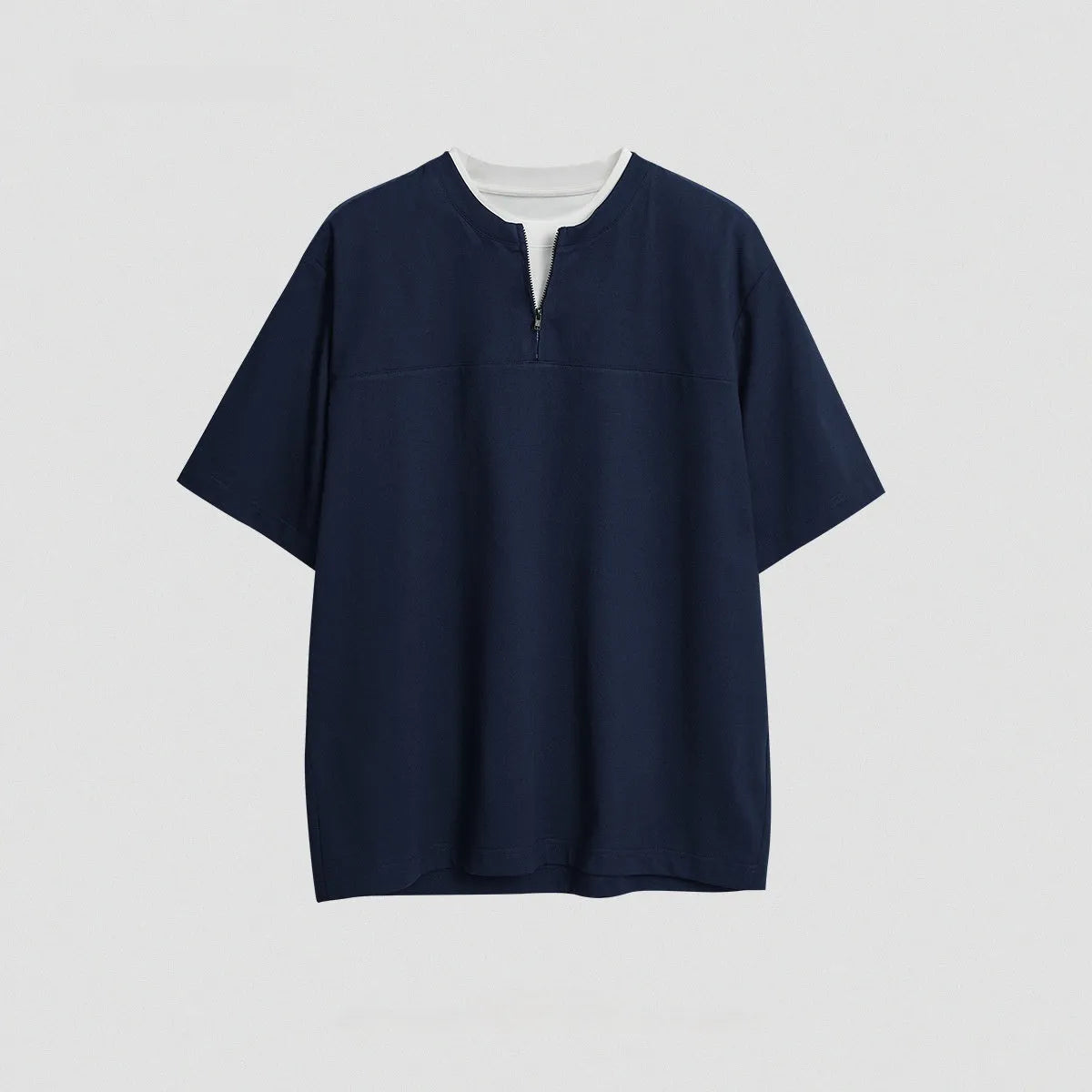 A solid colour loose-fitting casual top with zip detail and patchwork styling on a hanger.