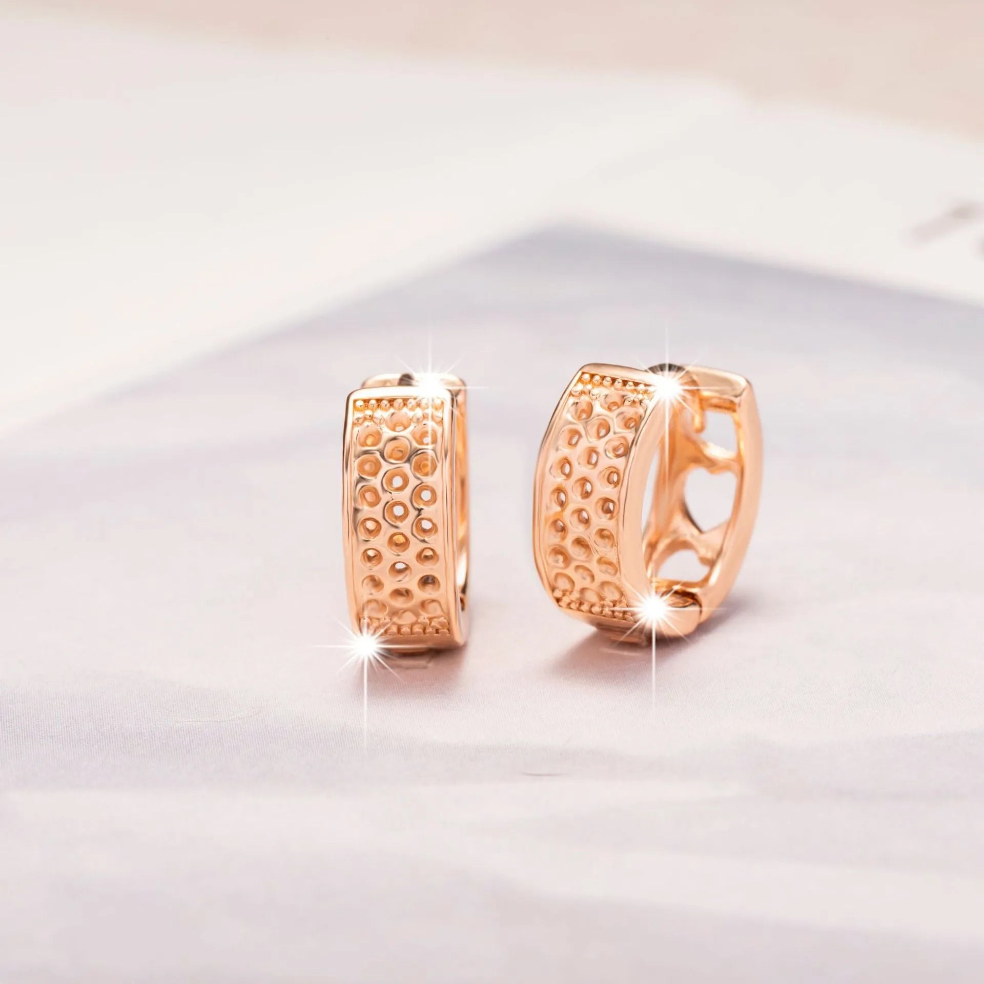 A pair of rose gold hollowed-out heart earrings on a white background, showing three-dimensional openwork detail.