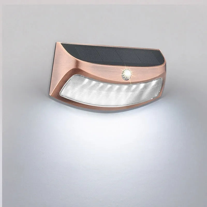 Solar-powered outdoor wall lamp with a smiling face design in a garden setting.