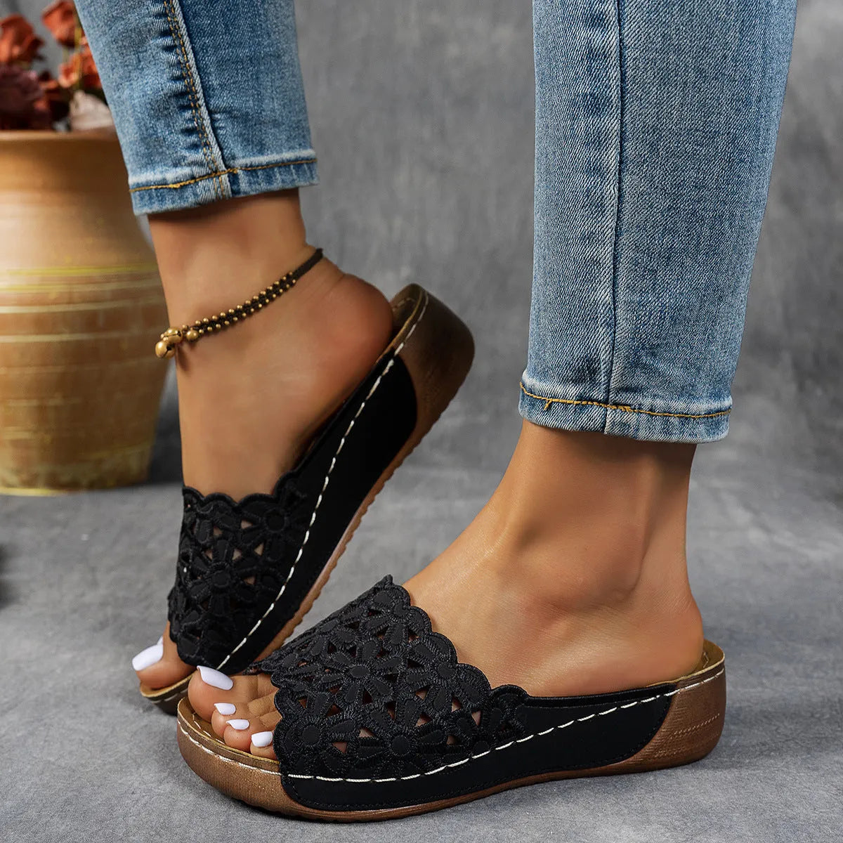 Women's black beach slippers with a flower cutout design on the upper and a wedge-style rubber sole.