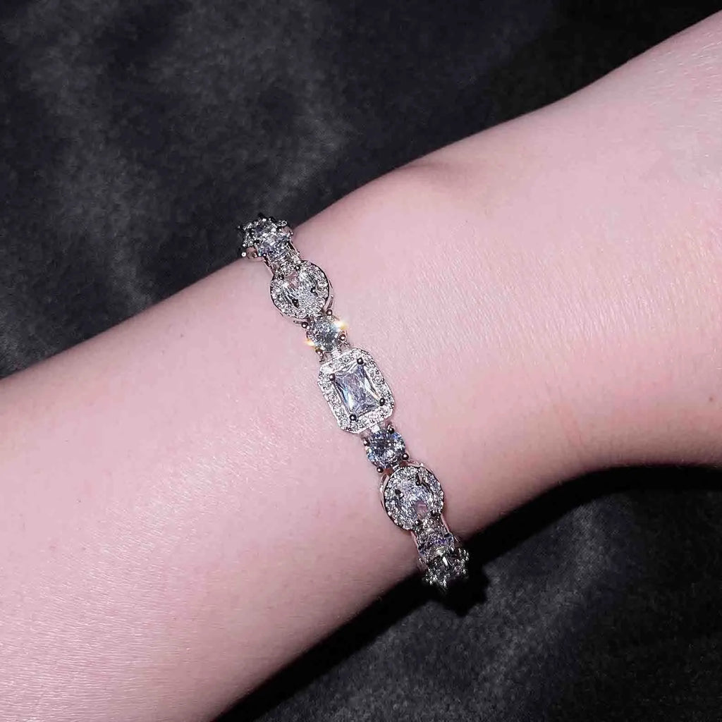 Close-up of women's geometric silver bracelet with inlaid zircon stones on a wrist, showing adjustable chain links.