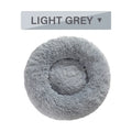 A fluffy, round donut-shaped dog bed with a raised rim in long plush fabric.