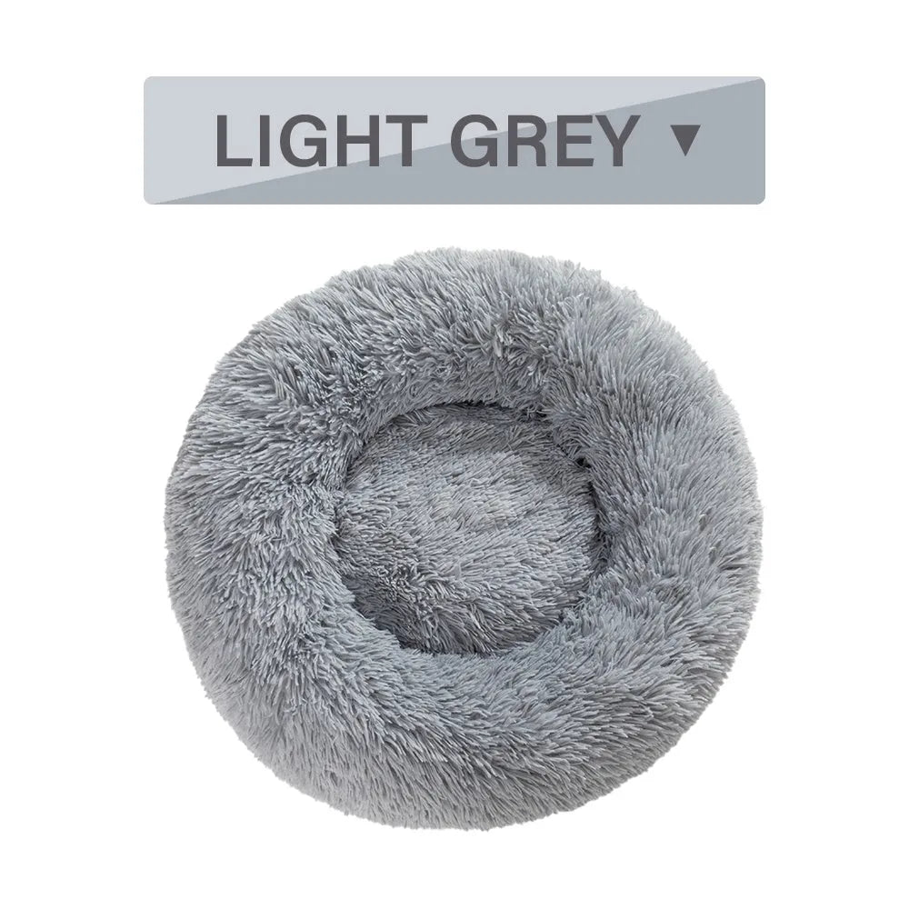 A fluffy, round donut-shaped dog bed with a raised rim in long plush fabric.
