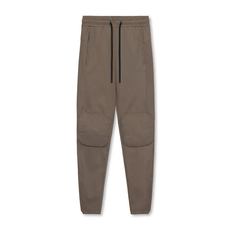 Man wearing dark grey loose-fit fitness trousers with tied ankles, made of quick-dry polyester blend fabric.