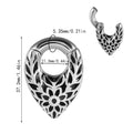 Close-up of a stainless steel drop-shaped ear extender with totem patterns, hanging vertically.