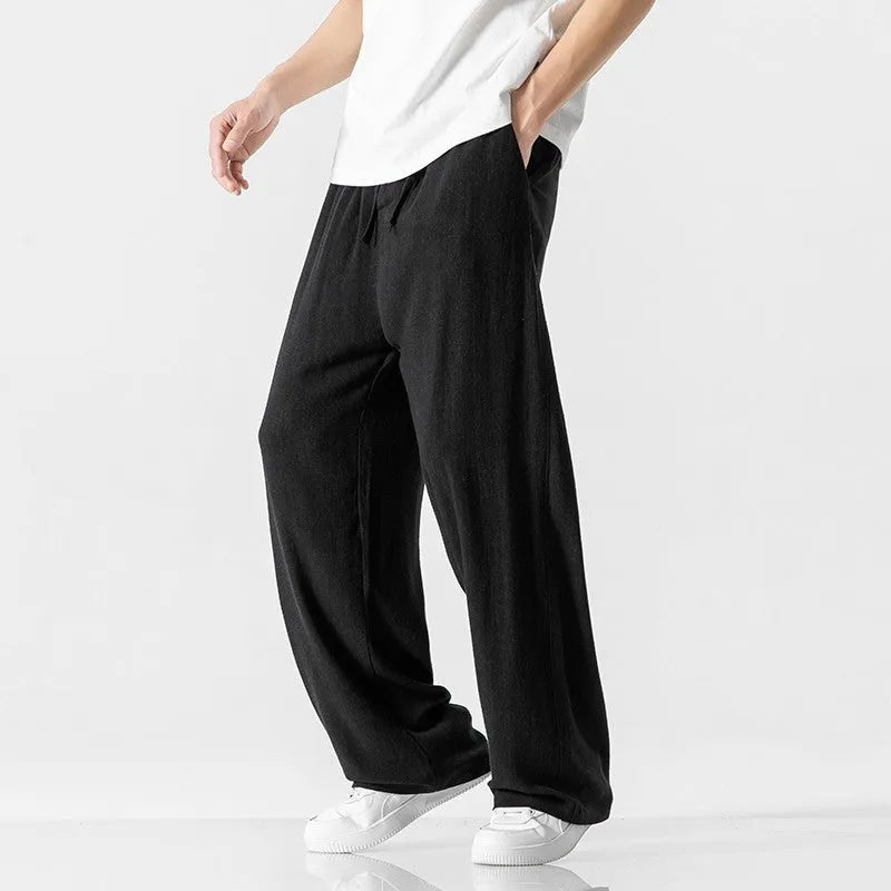 Man wearing beige straight-leg linen bamboo fibre trousers with a drawstring waist and cropped ankle length.