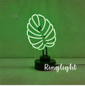 Minimalist white bamboo-shaped desk lamp emitting a soft green glow from its tube.