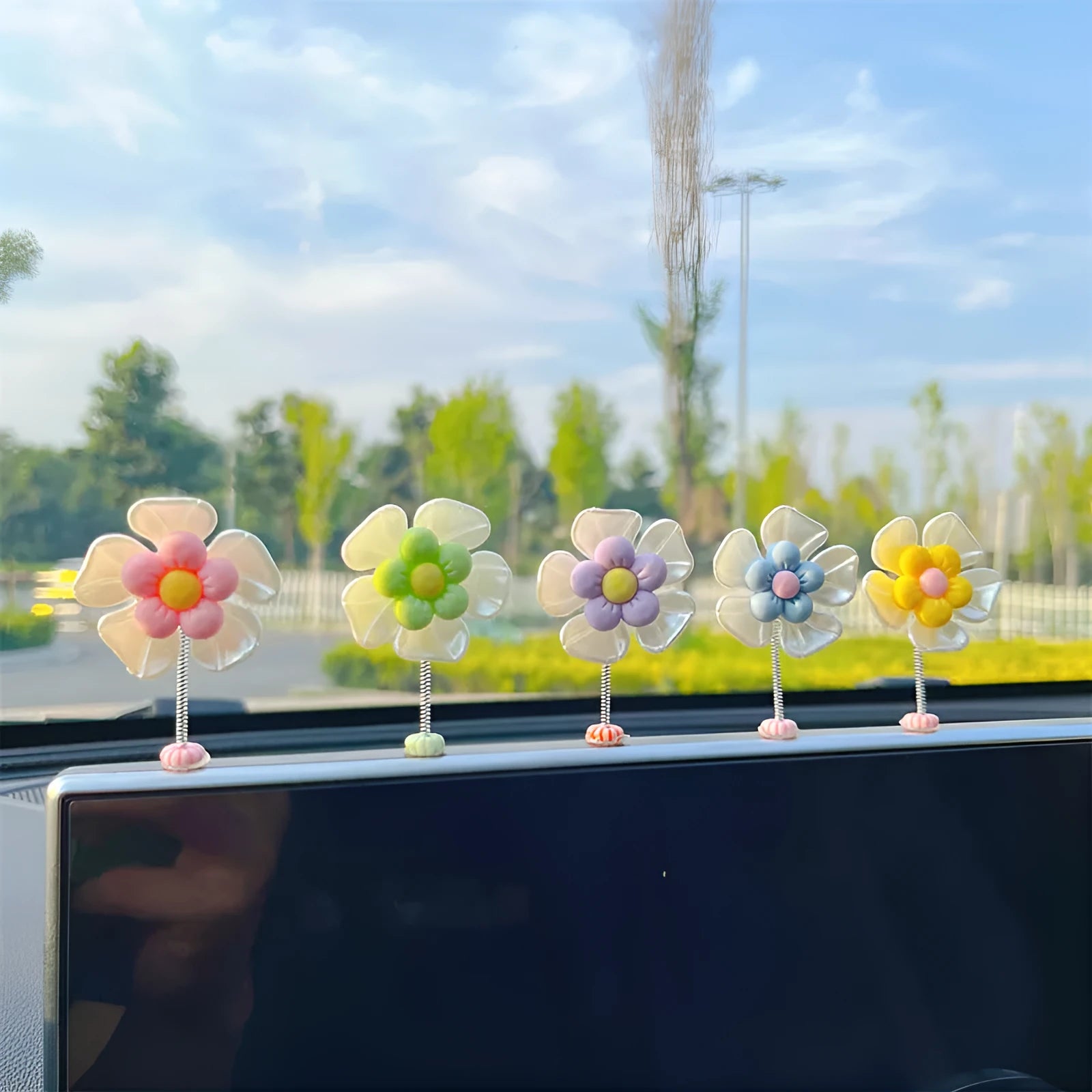 Small colourful plastic swing ornament for car dashboard, shown in blue, green, pink, purple, and yellow.