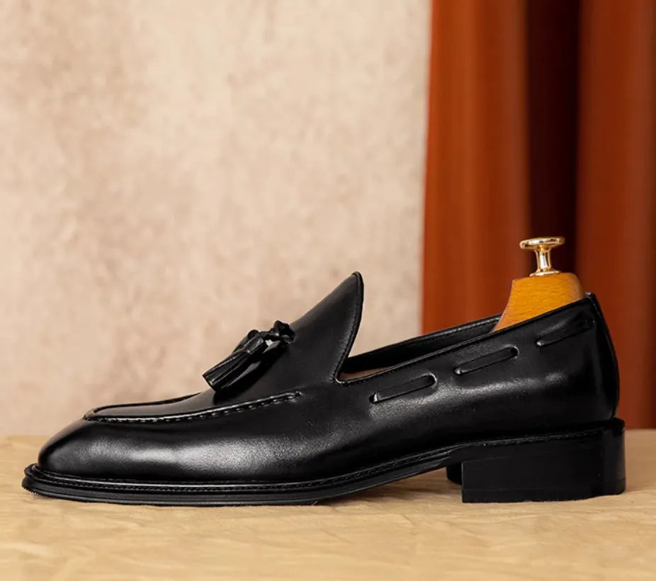 Men's black and brown genuine leather slip-on loafers with a fringed detail and rubber sole.
