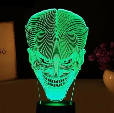 A 3D acrylic LED lamp on a base, showing a colourful gradient light effect, with a remote control beside it.