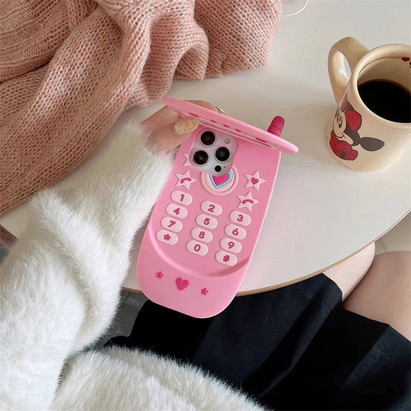 Pink silicone iPhone case shaped like a flip phone with a built-in mirror on the front.