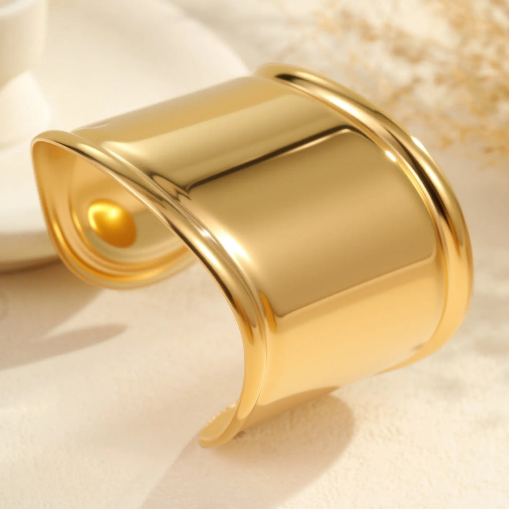 Women's wide stainless steel bracelet with 18K gold plating in a wave and geometric design.