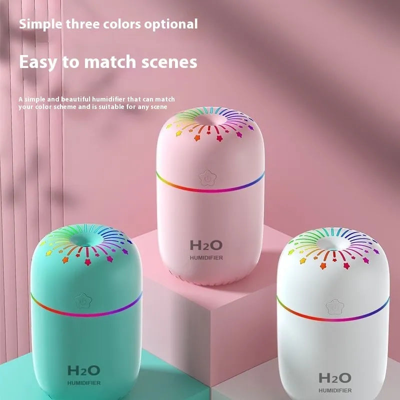 Small white USB humidifier with water tank on a wooden desk next to a laptop.