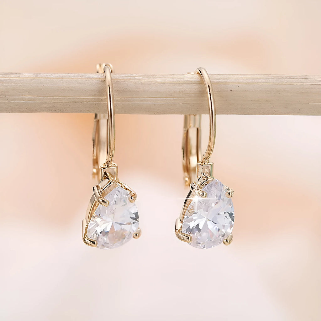 A pair of simple drop-shaped copper earrings with a platinum gem setting, shown in gold colour.