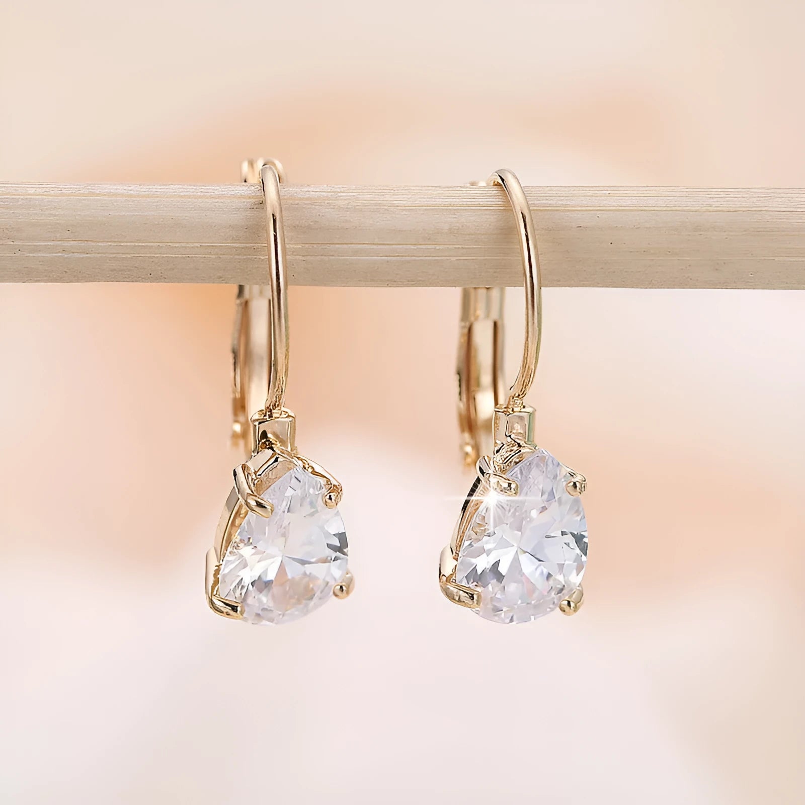 A pair of simple drop-shaped copper earrings with a platinum gem setting, shown in gold colour.