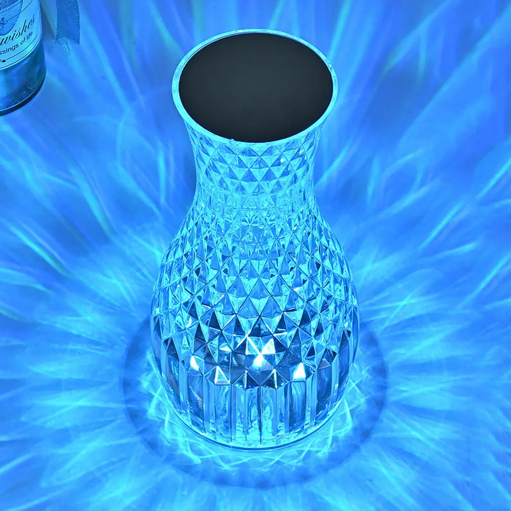 Vase-shaped crystal table lamp with LED lights and remote control on a bedside table