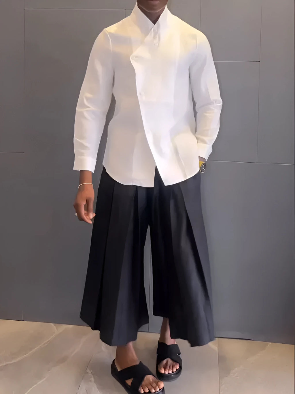 White asymmetrical shirt and black pleated trousers co-ordinate set laid flat