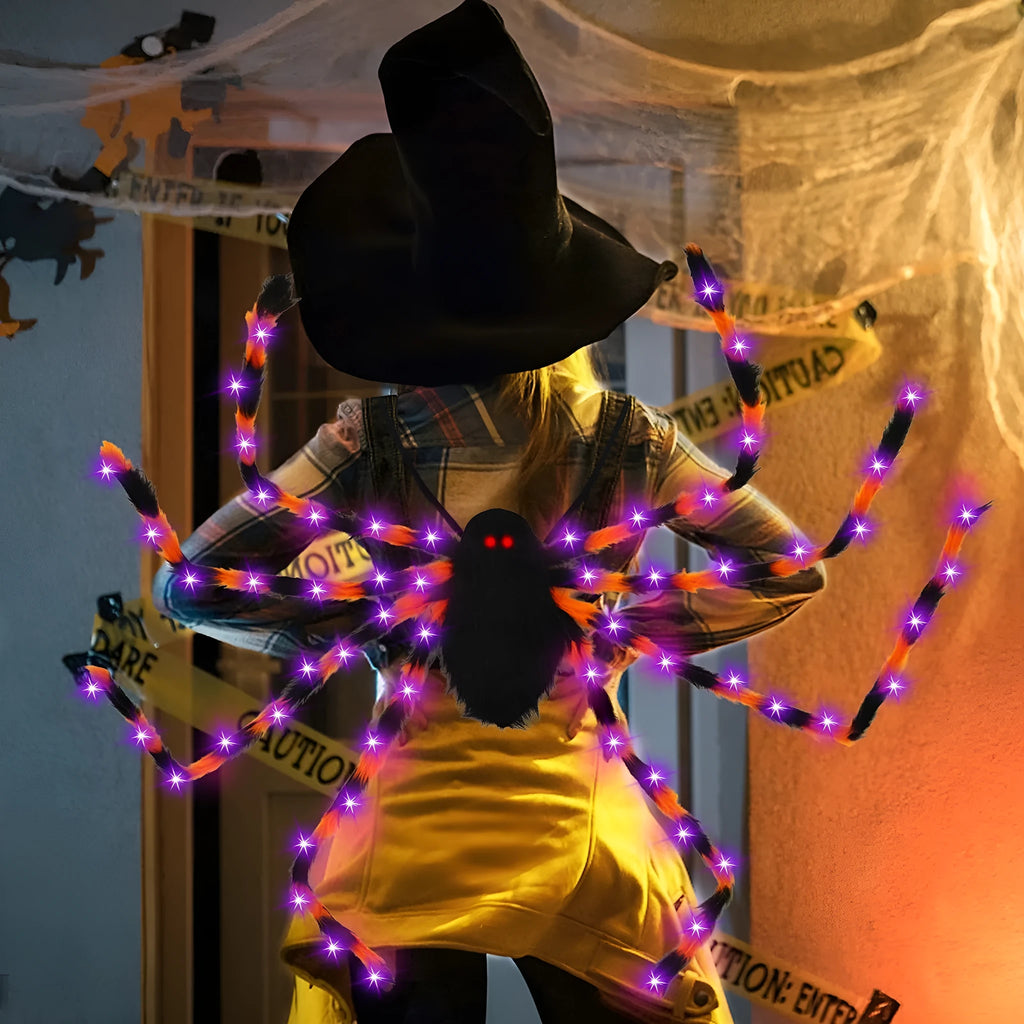 Orange plush Halloween spider backpack with purple LED lights lit up, showing the candy bag design.