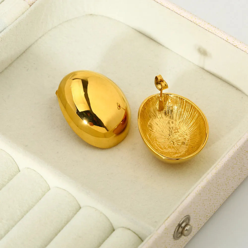 A pair of geometric gold-coloured ear studs with a glazed reflective surface and linear design details.