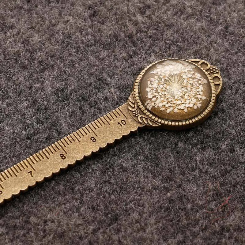 Handmade dried gypsophila and clover flower bookmark ruler on a book, showing 12cm length.