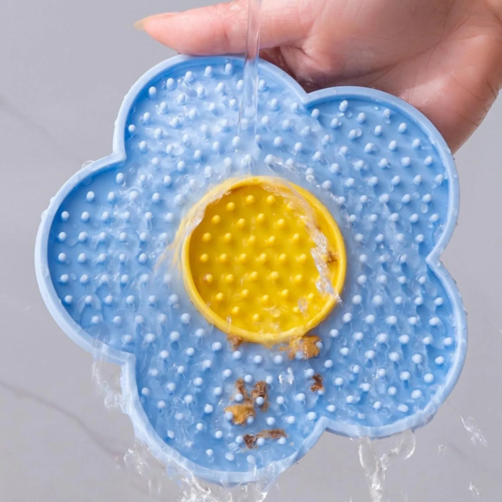 Flower-shaped silicone lick mat for dogs and cats with suction cups on a blue background.