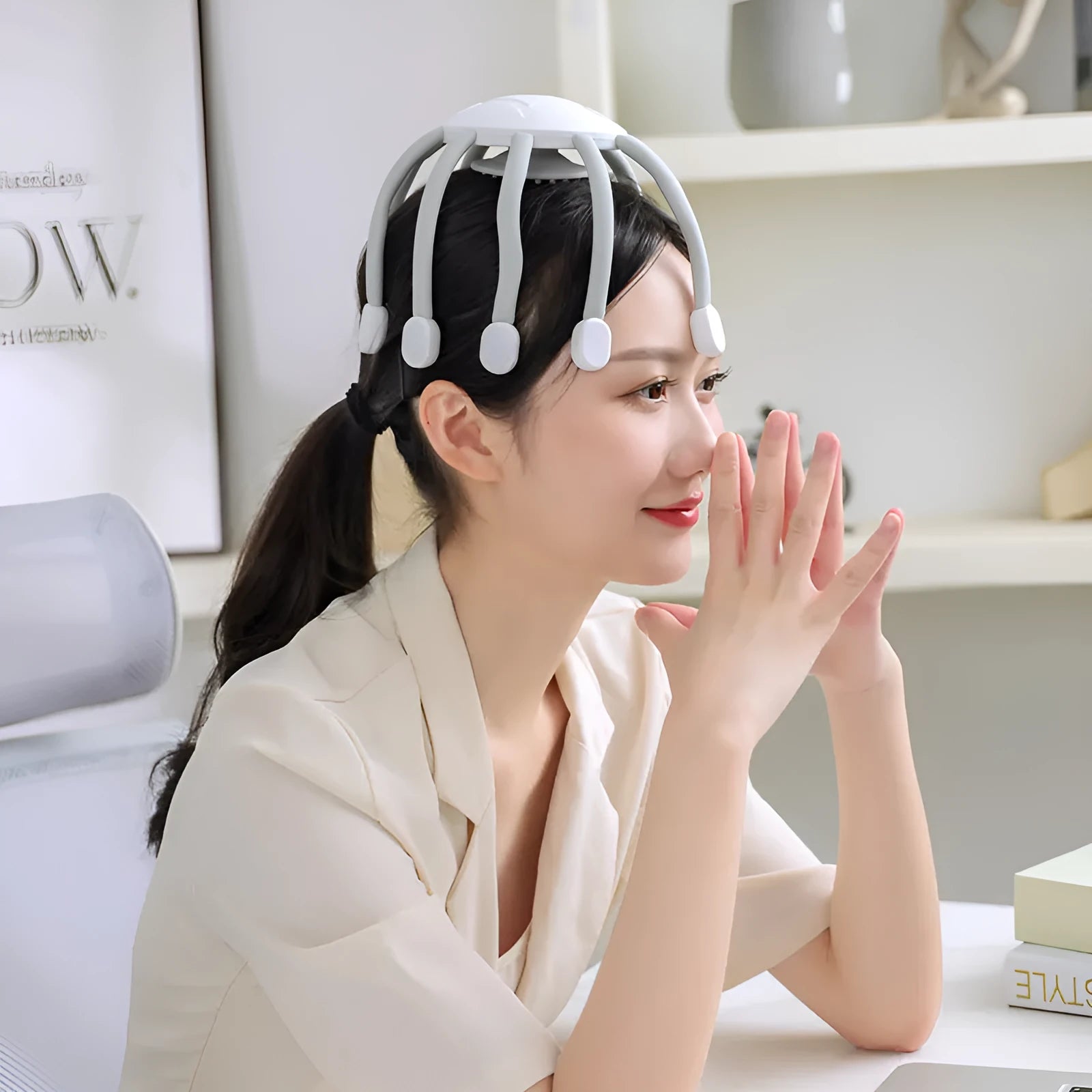 Black handheld head massager with eight extending claws showing silicone tips and control button