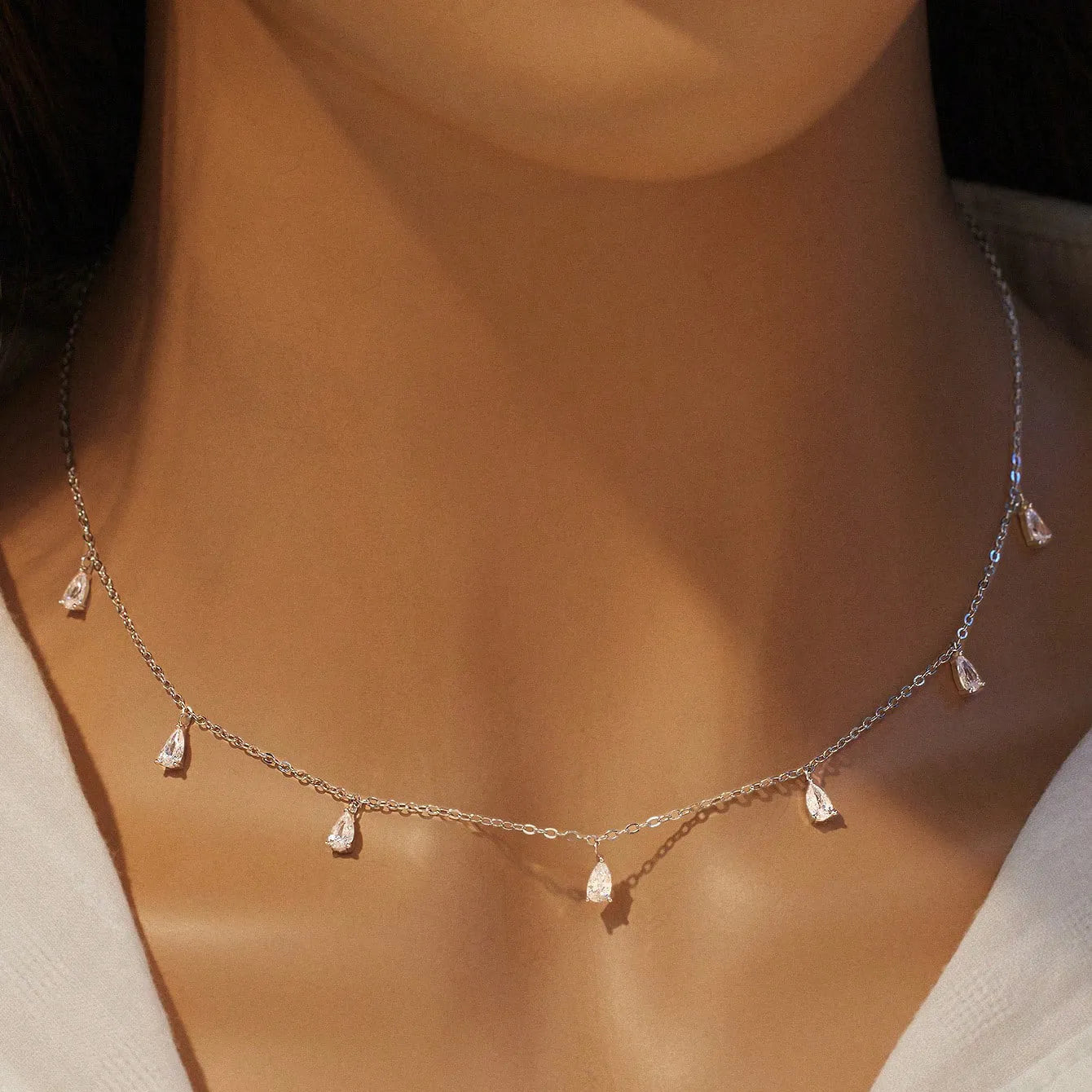 Women's silver necklace with a drop-shaped zircon pendant on an O-shaped chain, shown in golden yellow.