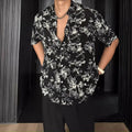 Loose-fitting black floral print short sleeve shirt on a hanger.