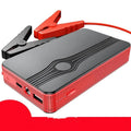 Red K4-E portable car jump starter and power bank unit with USB cable on a table.