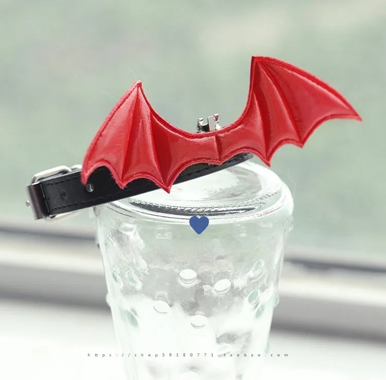 Split Home black patent leather choker collar with detachable devil wings and a central silver bell on an adjustable strap.
