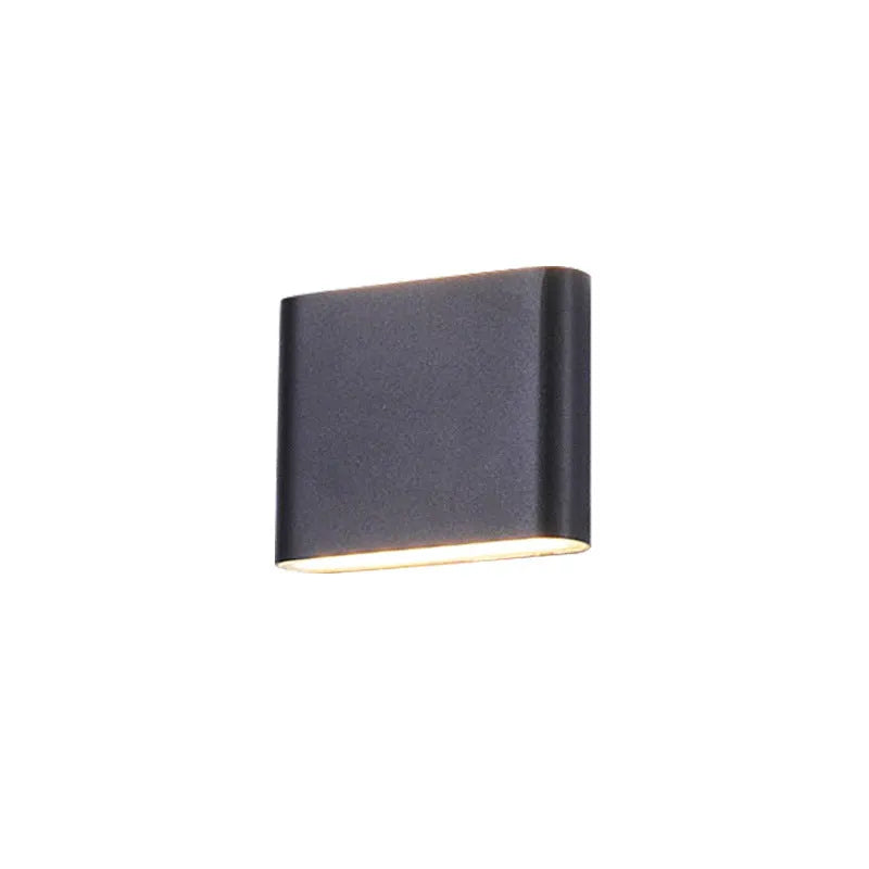 Rectangular LED outdoor wall lamp in black finish with warm light on a brick courtyard wall