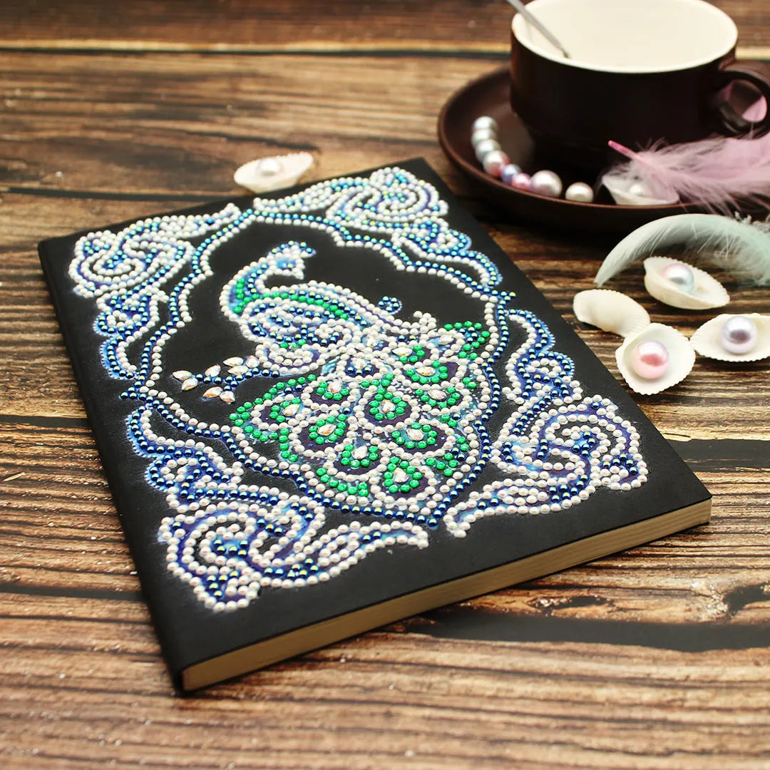 Peacock design diamond painting kit on a black A5 hardback notebook with drills and tools