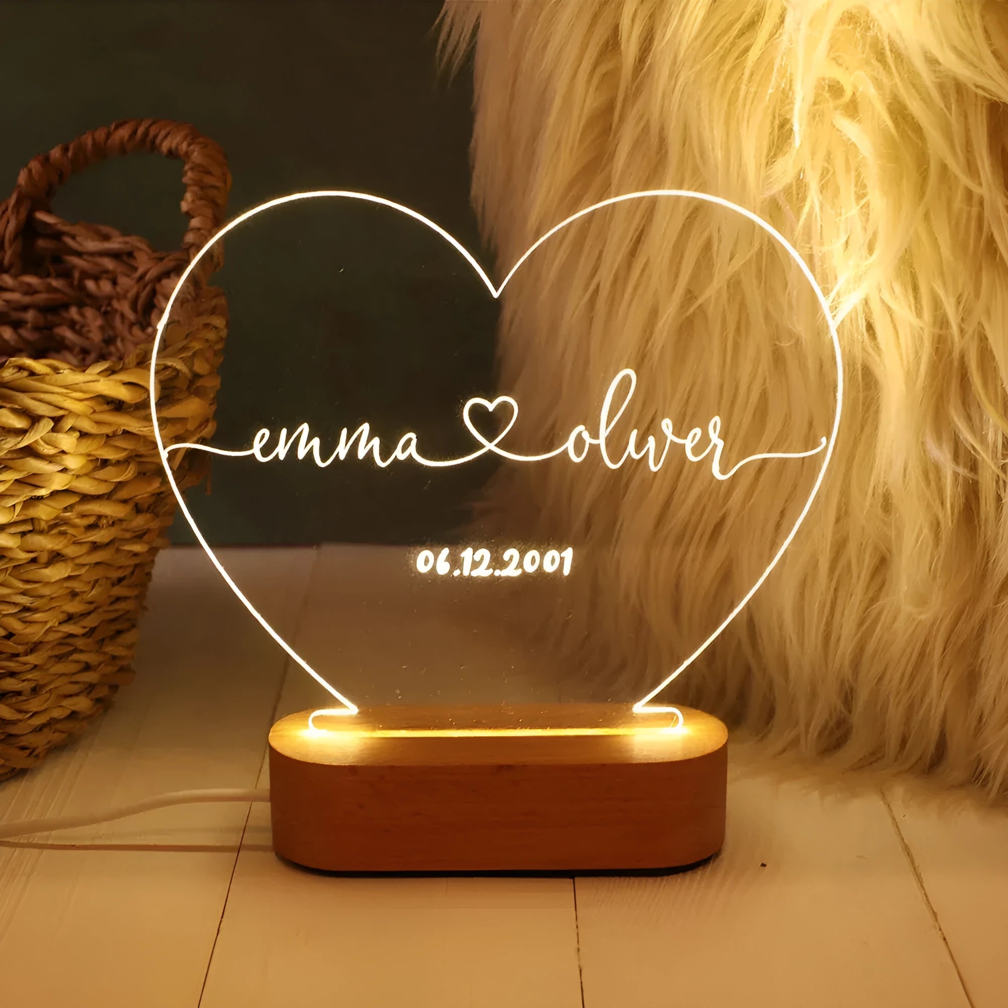 Custom transparent acrylic night light with engraved names and date, lit by an LED base on a table.