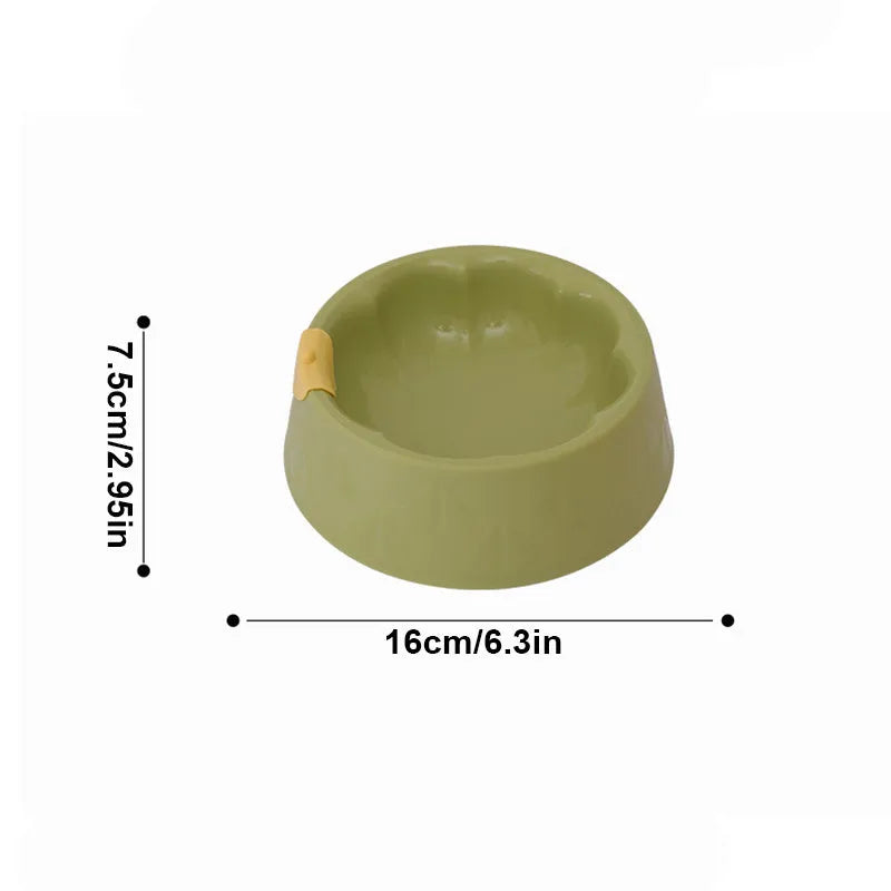 Green plastic double pet bowl for cats and small dogs on a floor.