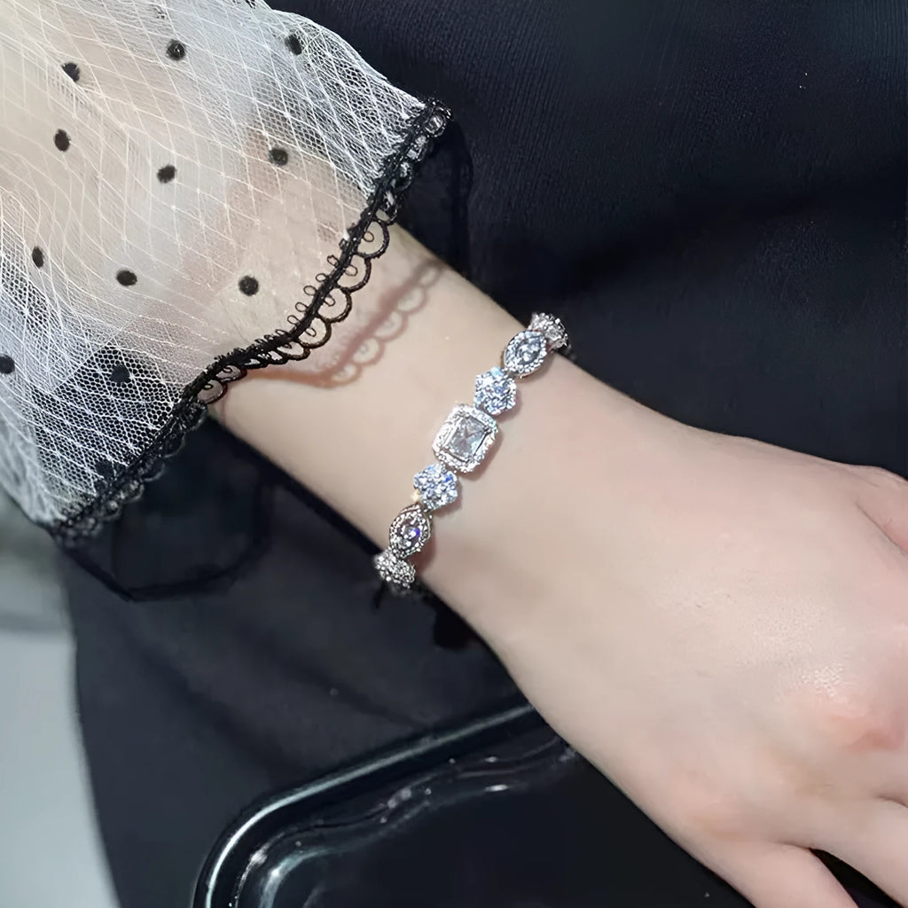 Close-up of women's geometric silver bracelet with inlaid zircon stones on a wrist, showing adjustable chain links.