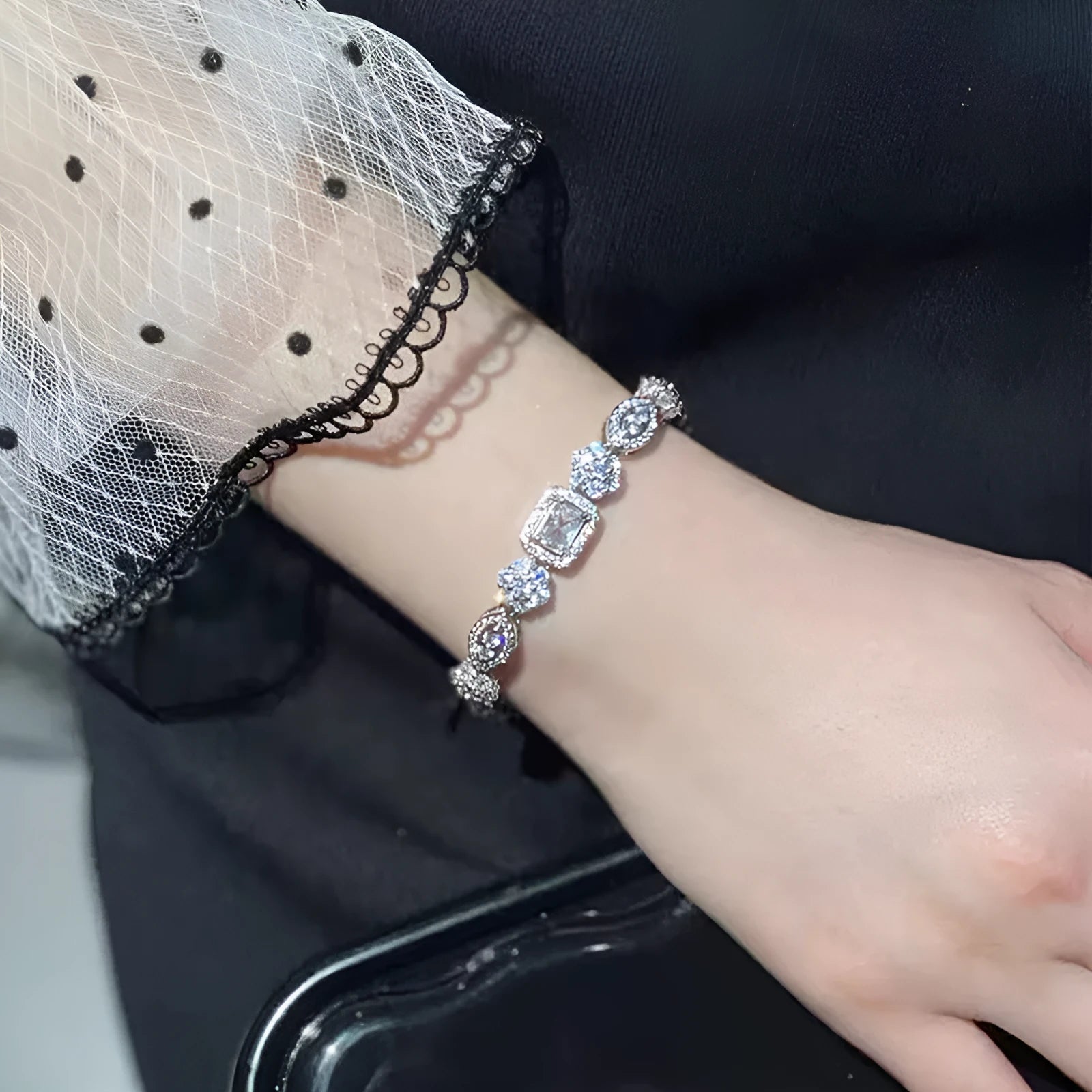 Close-up of women's geometric silver bracelet with inlaid zircon stones on a wrist, showing adjustable chain links.